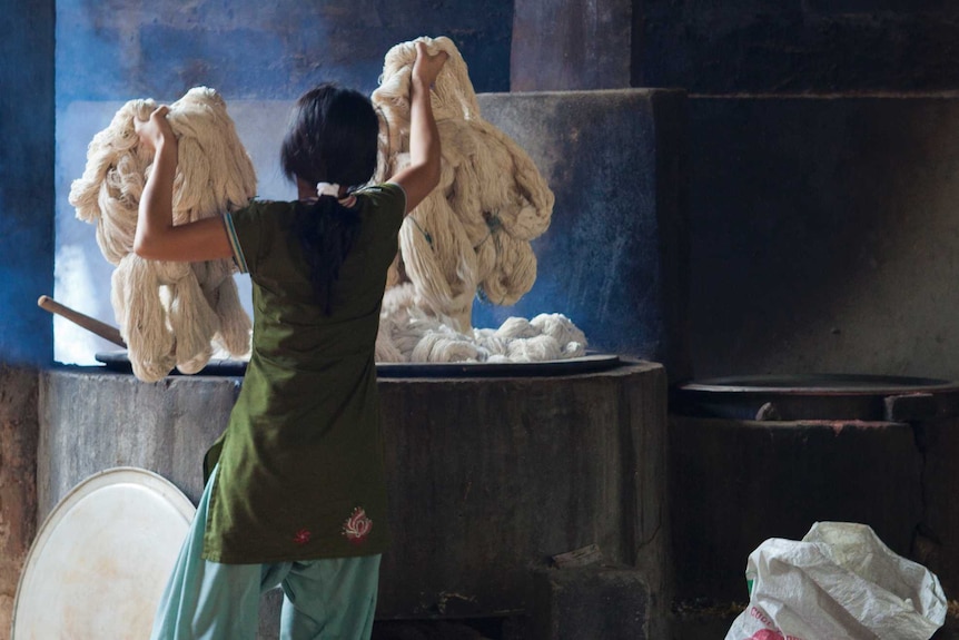 A woman adds plain cotton to hot dye at Womens Skills Development Project in Pokhara, Nepal.