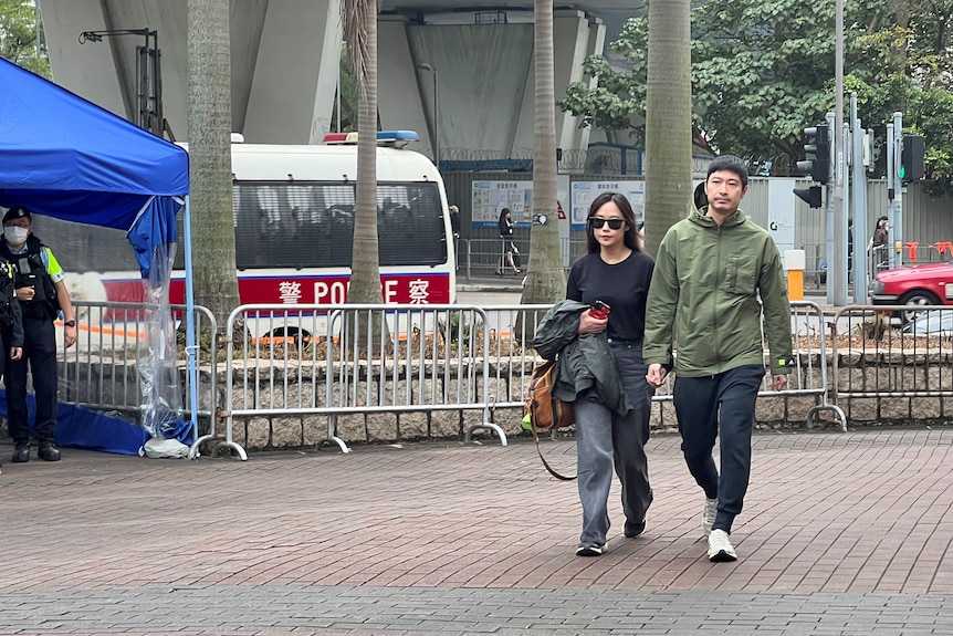 A man and woman walk on a Hong Kong sidewalk 