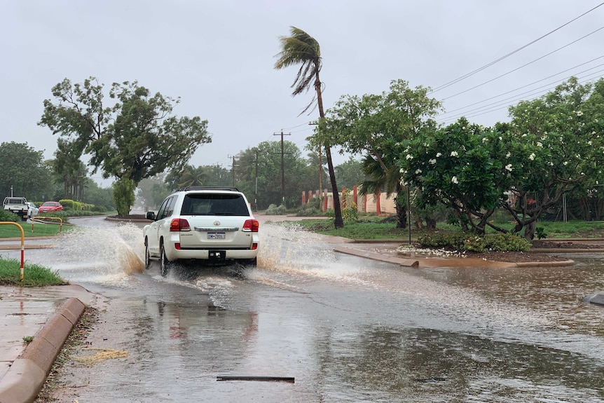 Car driving through floods in suburban street.