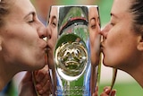 Melbourne City's Steph Catley (left) and Lauren Barnes kiss either side of the W-League trophy.