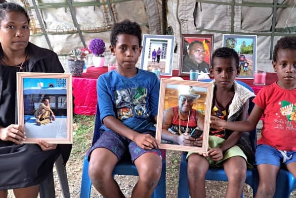 Flora Gwale and their three children holding photos of their late father and husband. 