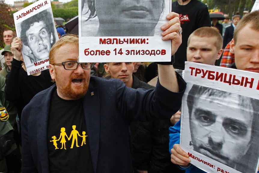 Vitaly Milonov holds a photo of a convicted paedophile at a rally to mark International Day Against Homophobia and Transphobia.