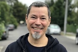 Ed Moreno smiles while standing on a suburban street.