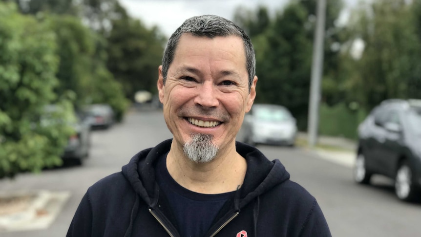 Ed Moreno smiles while standing on a suburban street.