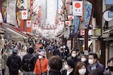 A street filled with a crowd of people wearing masks.