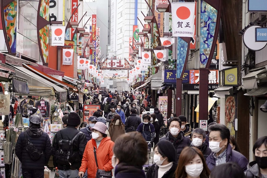 A street filled with a crowd of people wearing masks.