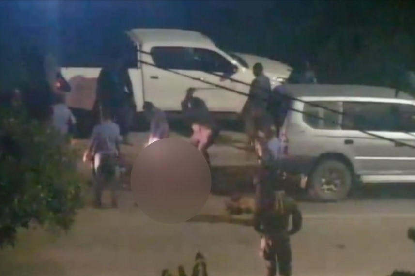 Police officers in Port Moresby are shown attacking men with sticks. The victims, who are lying down on a road, are blurred.