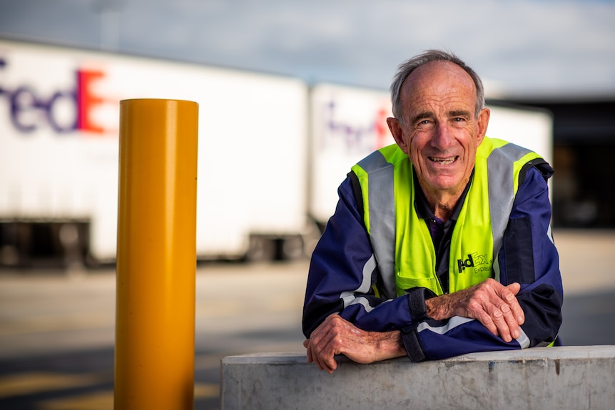 Barry Foreman smiles in front of a Fedex warehouse