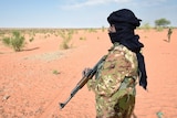 Man wearing holds gun in desert 