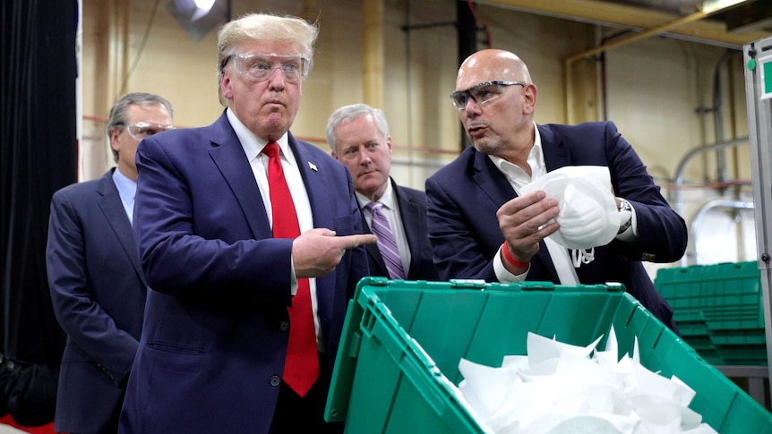 US President Donald Trump points to a face mask