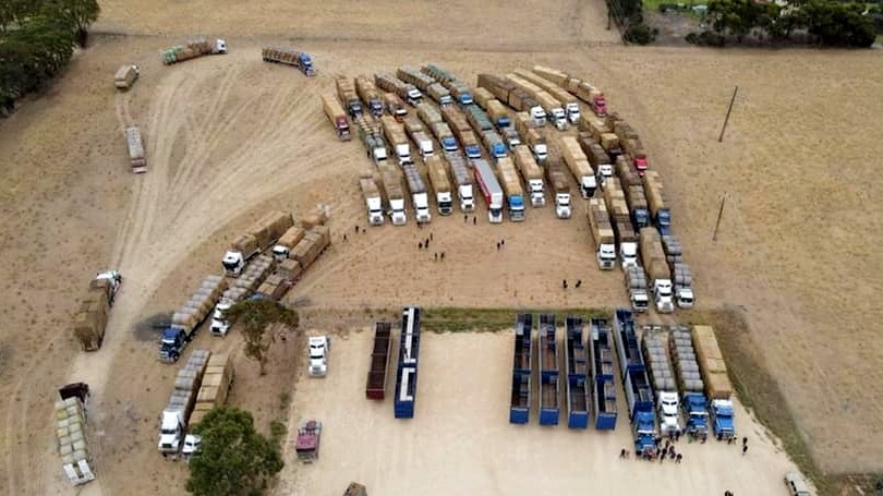 An aerial photo shows 40 trucks parked on a large grass field.