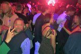 A large crowd of people standing in a room of a nightclub