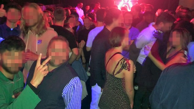 A large crowd of people standing in a room of a nightclub