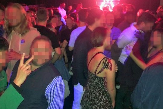 A large crowd of people standing in a room of a nightclub