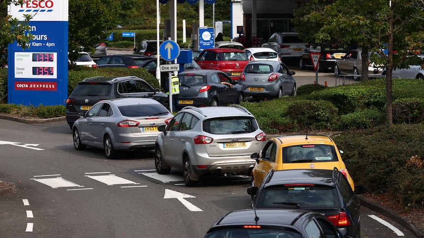 rear view of a long line of cars queuing in an S shape to get into a petrol station
