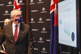 The Prime Minister, wearing an Australian flag mask, presents a powerpoint slide.