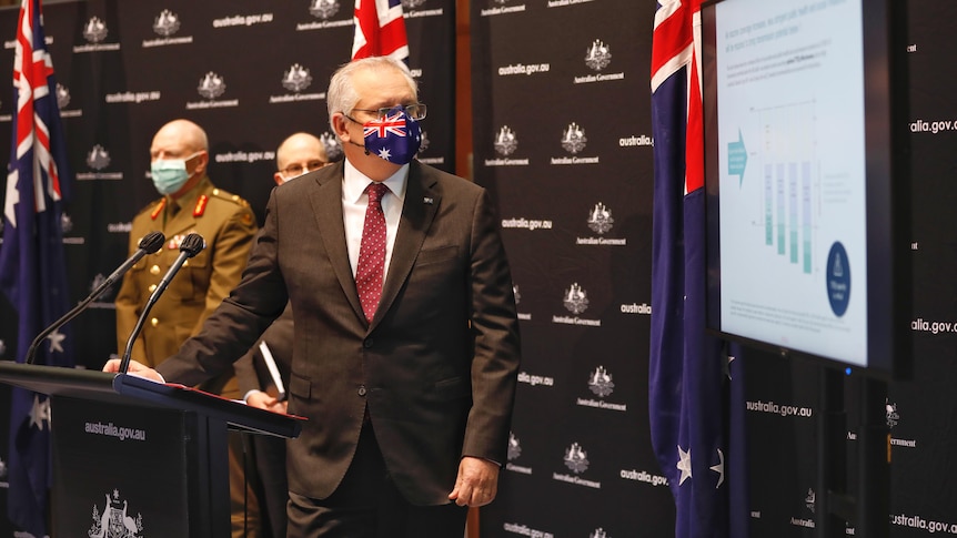 The Prime Minister, wearing an Australian flag mask, presents a powerpoint slide.
