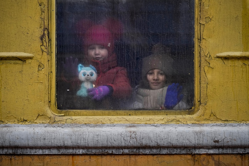 Children look out the window of an unheated Lviv bound train.