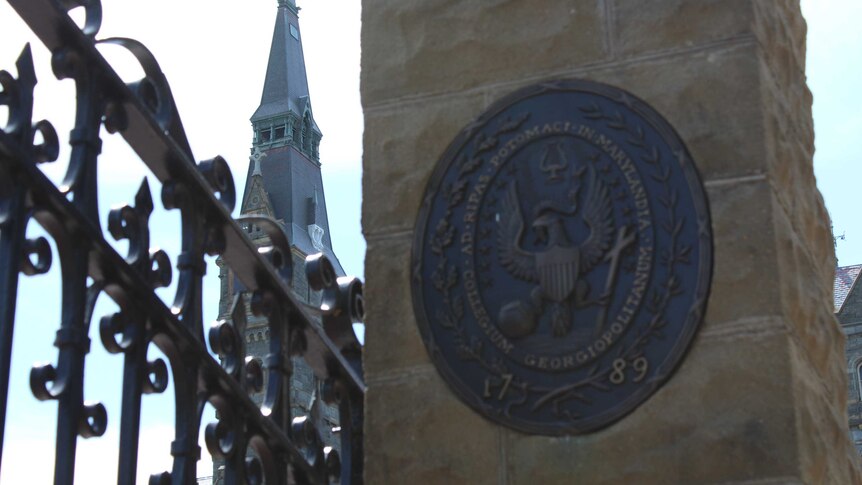 The logo to Georgetown University in Washington DC on a column, with a spire in the background.