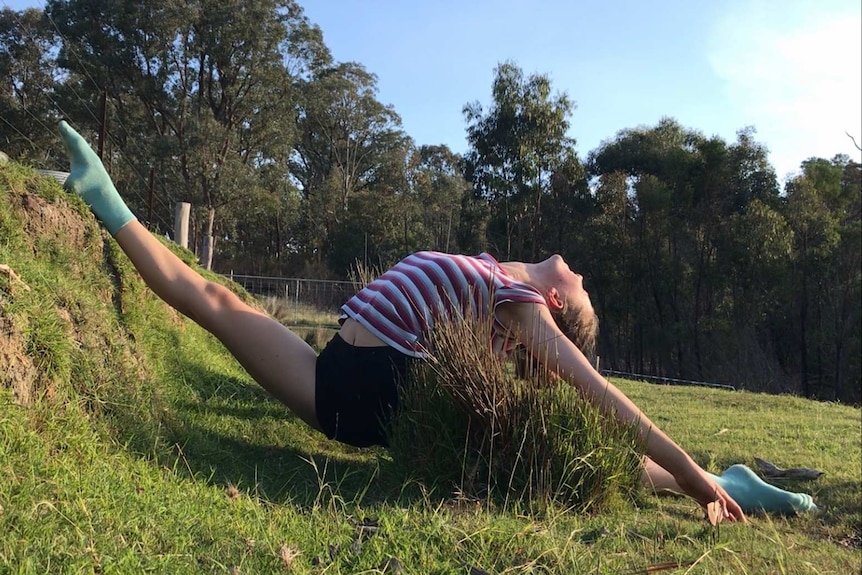 A young woman does the splits on the grass at a property