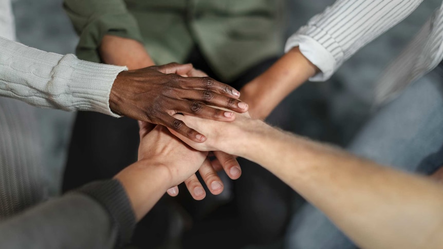 diverse hands joining together in a huddle