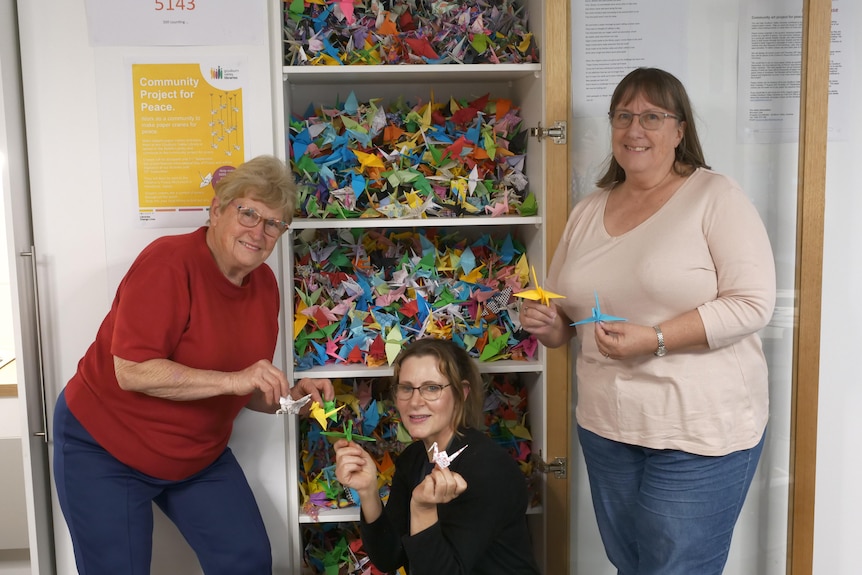 three women show off their collection of origami cranes 