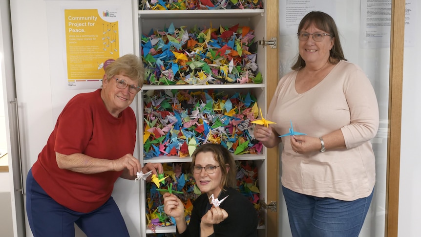 three women show off their collection of origami cranes 