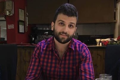 Mohammad smiles to the camera wearing a plaid shirt.