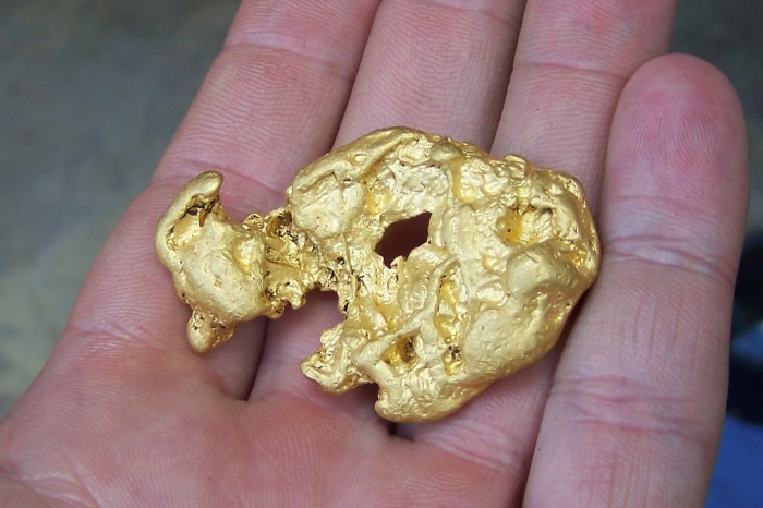 A gold nugget sitting in a man's palm