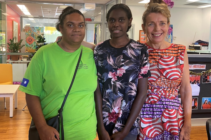 Three women wearing bright colours in a school