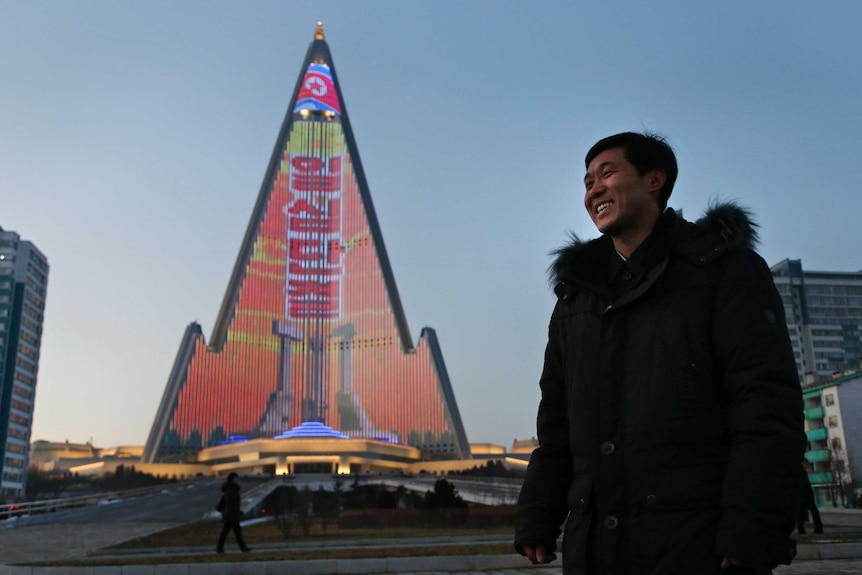 Light designer Kim Yong II smiles next to the Ryugyong Hotel.