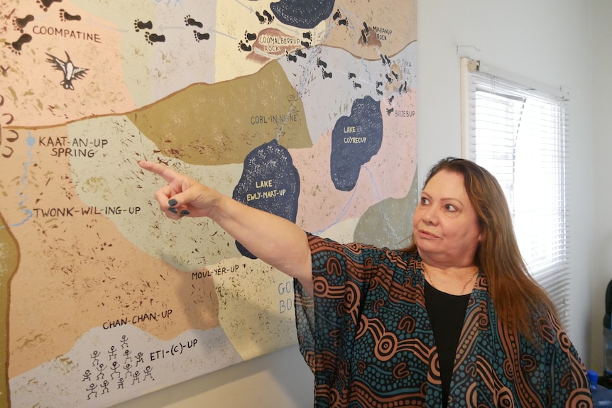 a woman points at a point on an Aboriginal map