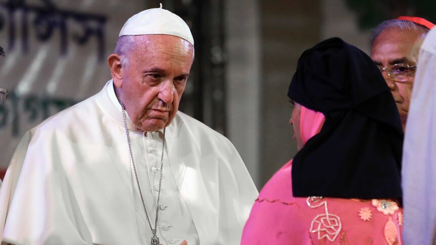 Pope Francis stands in front of a woman.