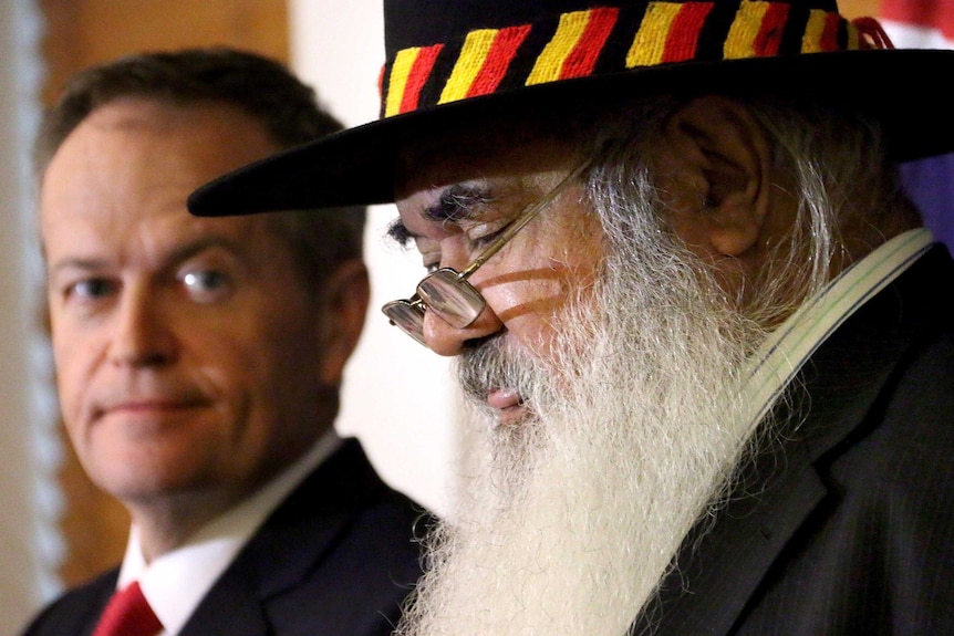 Tight photo of heads - Bill Shorten, out of focus, listens to Pat Dodson speak.