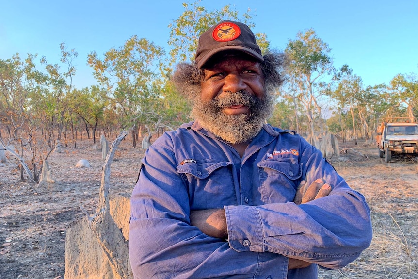 Alfred Hickson wearing a Mimal Rangers cap and blue work shirt stands in Arnhem Land.