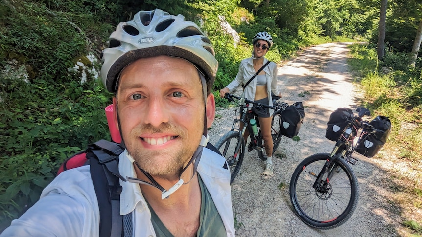 Kurt and his partner take selfie sitting on their bikes along a bike path 