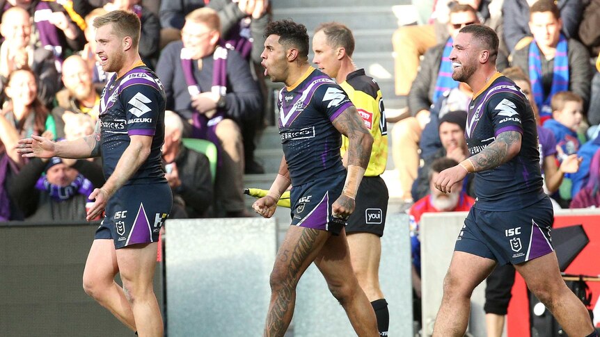 A group of NRL footballers walk back to halfway after scoring a try.