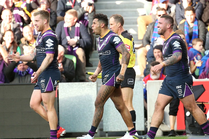 A group of NRL footballers walk back to halfway after scoring a try.