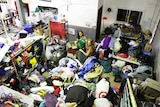 Two women sorting through a room full of clothing and household products.