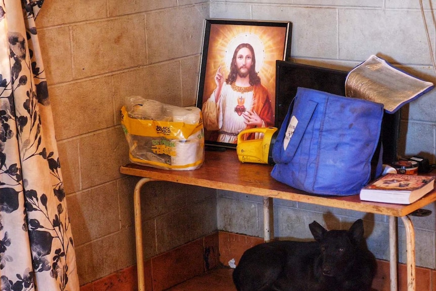 A picture of Jesus, a torch and other household items sitting on a small table.