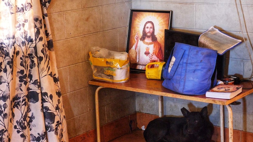 A picture of Jesus, a torch and other household items sitting on a small table.