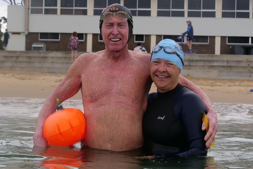 a smiling man and a woman in a wetsuit after an ocean swim