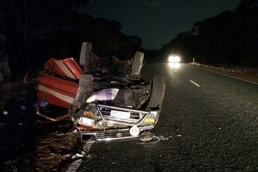 A four-wheel-drive sits upside down with its doors open on the side of the Coolgardie Esperance Highway after rolling over.