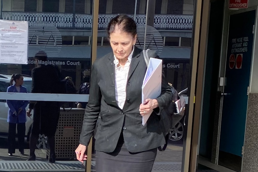 A woman in business suit carrying a white folder walking down steps