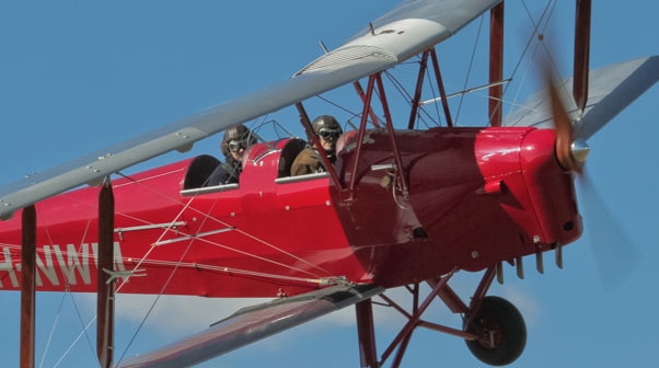 Two people flying in a red tiger mother aircraft