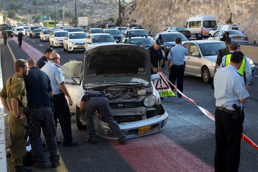 Israeli policemen inspect the damaged car of a Palestinian woman after she detonated a small bomb