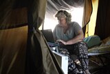 Woman on a laptop inside a tent.