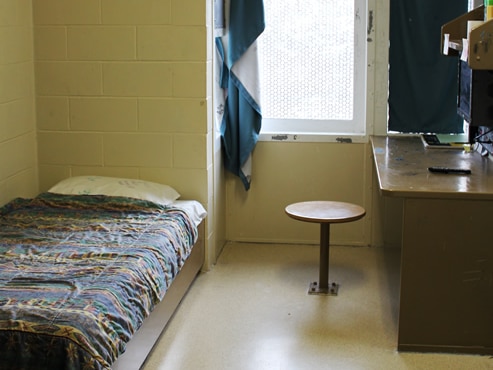 A single bed against the wall. A desk next to the window. 