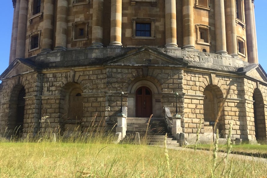 A grand Oxford building with wild long lawn.