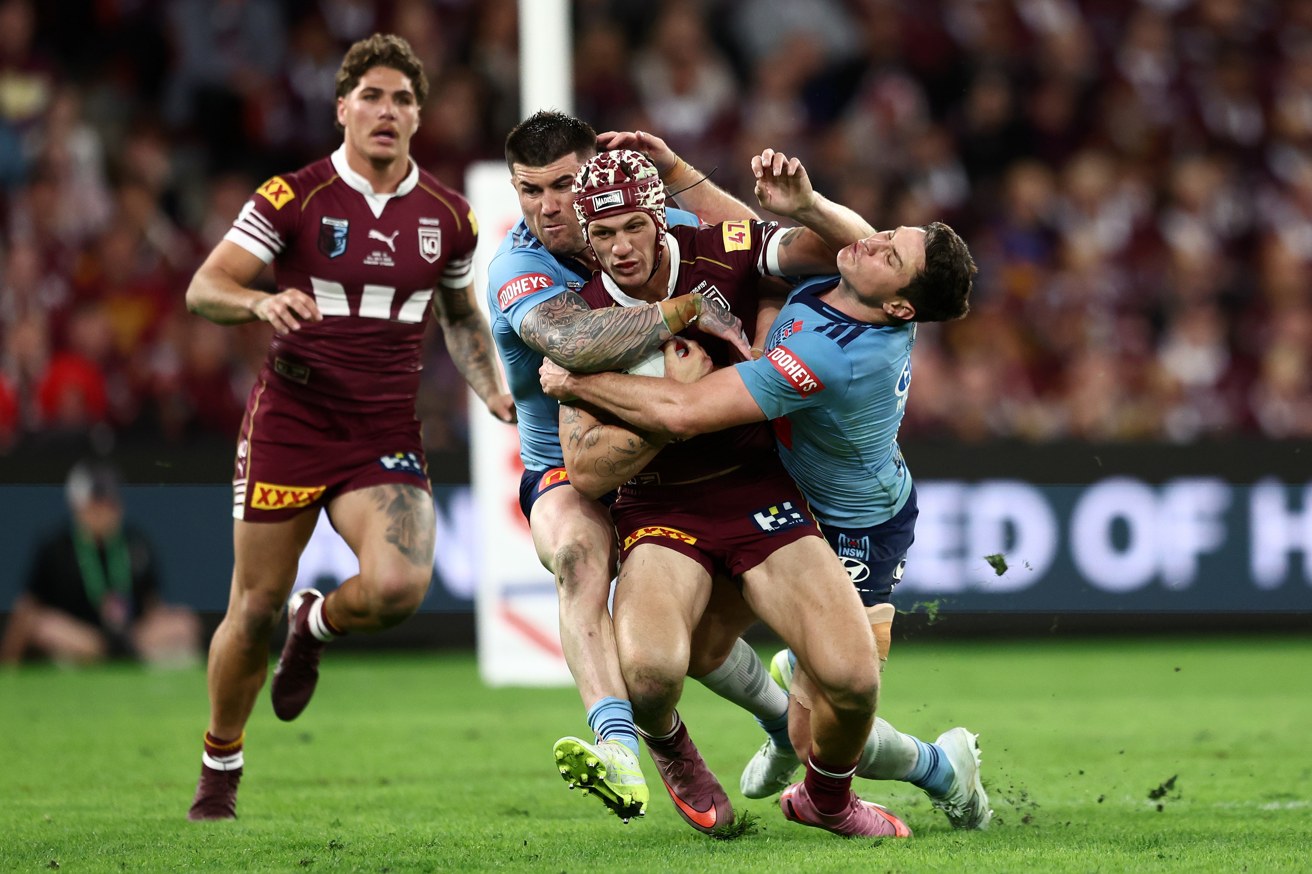 Kalyn Ponga is tackled by Blues as Reece Walsh watches on.